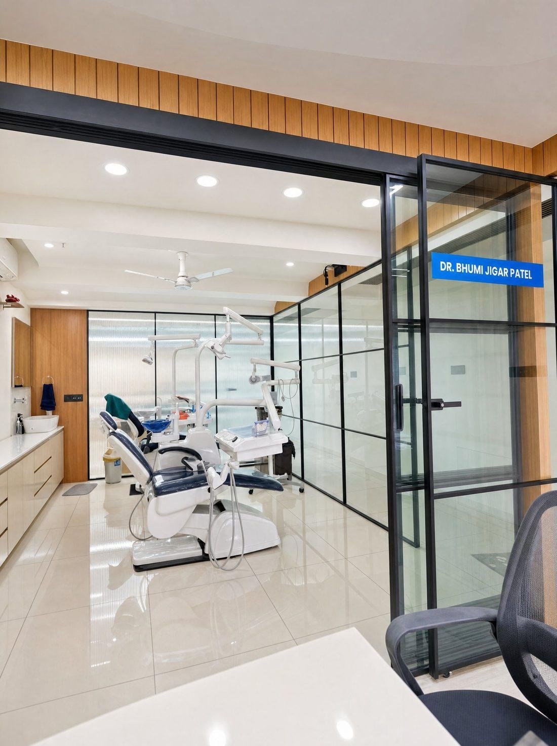 Inside Divine Dental & Skin Clinic in Sola, Ahmedabad — dental treatment room behind the glass partition marked &lsquo;Dr. Bhumi Jigar Patel&rsquo;